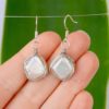 Hand scale of sustainable silver wire wrapped ivory pearl earrings