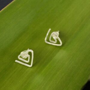 Eco Silver Textured Triangle Spiral Studs against a green leaf background
