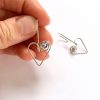 Recycled Silver Heart dangle earrings being held in the hand to show scale