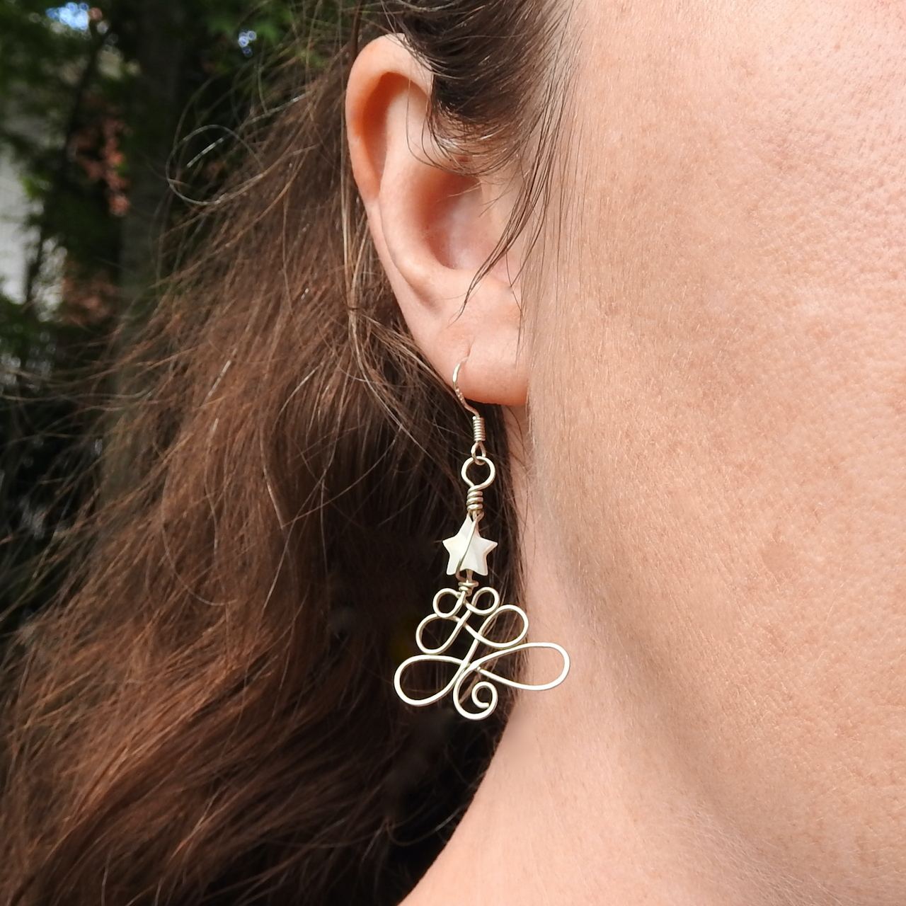 Front on photo of model wearing the Christmas tree earrings with white star
