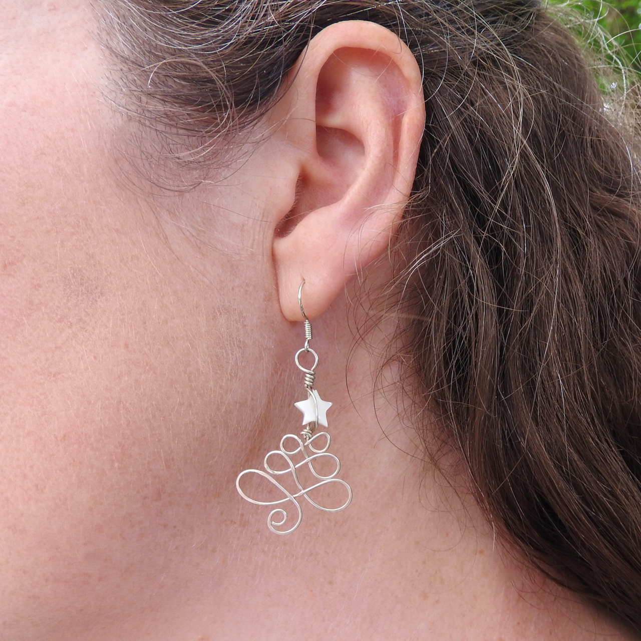 Side on photo showing a model wearing the Christmas Tree earrings with white Mother of Pearl star