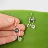 Curlicue Earrings with spirals at each end and a suspended freshwater pearl