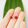 Hand scale of dark red Swarovski Pearl small drop earrings