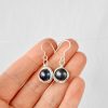 Hand scale view of black cultured pearl handmade earrings wrapped in environmentally friendly silver