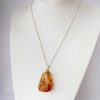 front scale view of NZ Amber Silver crossover necklace hung on white stand