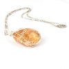 Angled view of clover honey coloured sterling silver wire wrapped double koru new zealand amber necklace