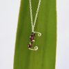 kids personalised necklace letter E with garnets hung against green background