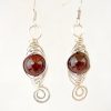 Close up of garnet birthstone earrings wire wrapped in eco silver