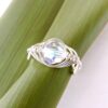 Top view of handmade eco silver pea pod birthstone ring on flax leaf