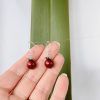 Hand-scale showing the burgundy Swarovski Pearl Christmas Ornament Earrings