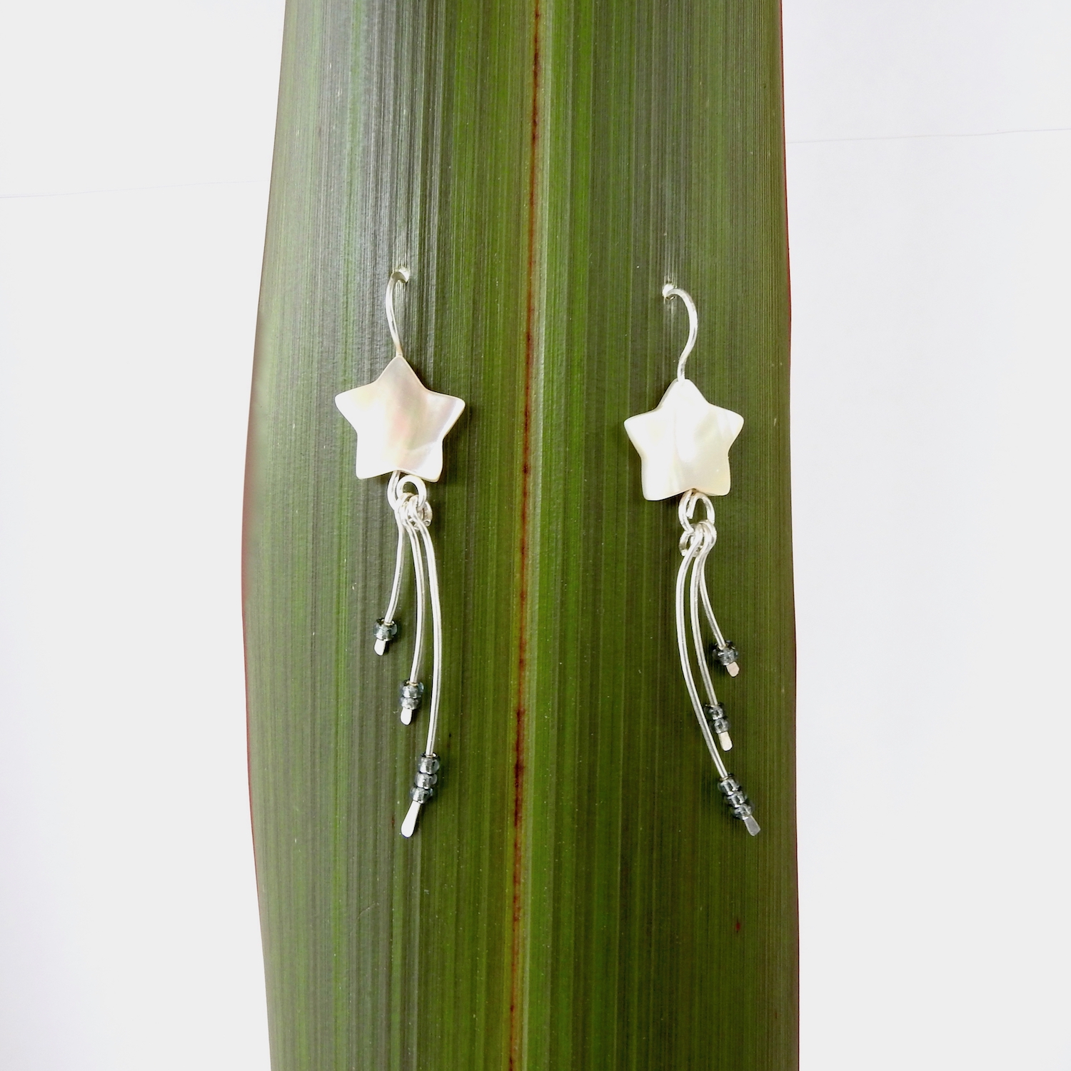 Wishing Star Earrings - like a shooting star - against flax background