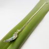 Angle view of curved paua shell necklace on flax leaf