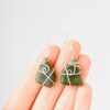 Hand scale of trapezoid shaped NZ Greenstone earrings wrapped in recycled Sterling Silver wire