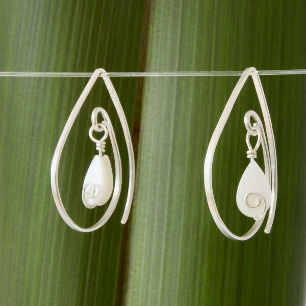 Mother of Pearl Tear Drop Limited Edition 10th biz birthday earrings, shown front on in front of flax