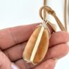 Hand showing back of Kauri Gum neckalce_white background