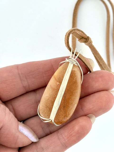 Hand showing back of Kauri Gum neckalce_white background