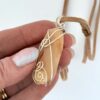 Hand showing front side of Kauri Gum neckalce_white background