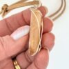 Hand showing right side of Kauri Gum neckalce_white background