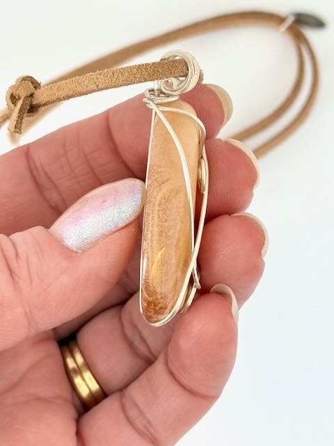 Hand showing right side of Kauri Gum neckalce_white background